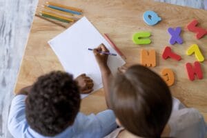 Young boy practicing letter formation and handwriting skills at the table