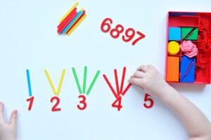Child's hands building hands-on math activities with number and shape materials for preschool