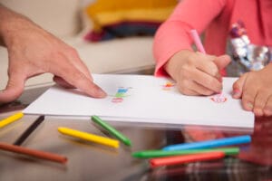 Close-up of child's hands practicing fine motor skills drawing with pencil on paper